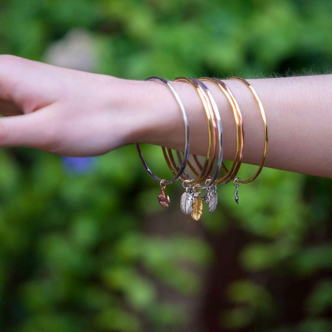 close up of model wearing multiple feather bangles