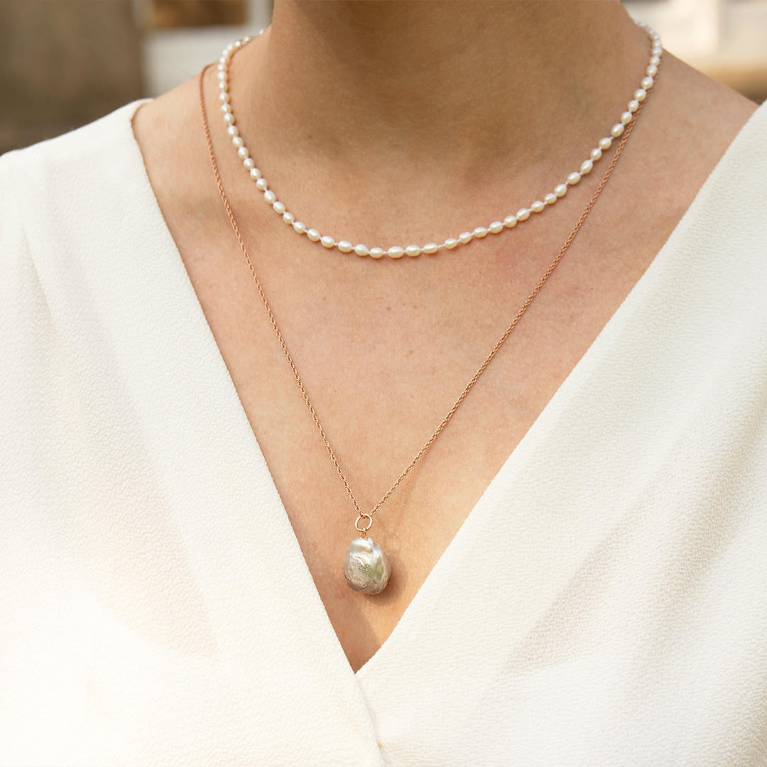 Ivory seed pearl necklace on a model with a baroque pearl pendant