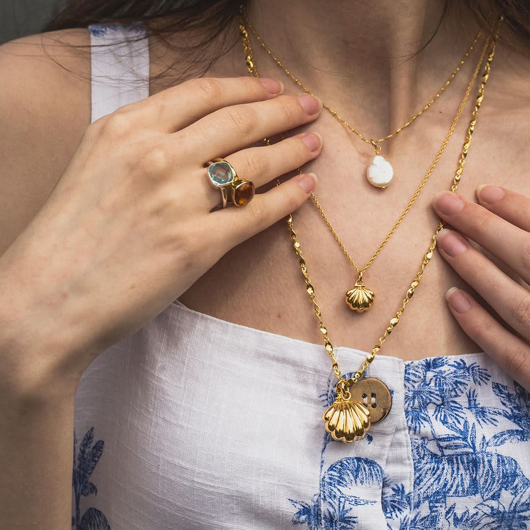 model wearing gold seahorse locket on a gold belcher chain