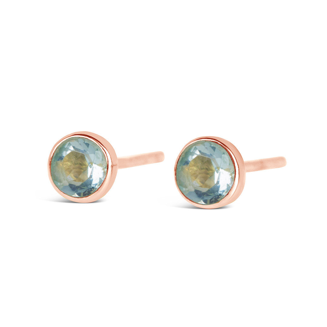 Blue topaz mini stud earrings in rose gold facing the front on a white background