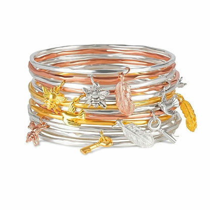 stack of charm bangles with different metal types and charms