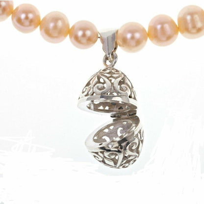 closeup of opened keepsake egg necklace in champagne on a white background