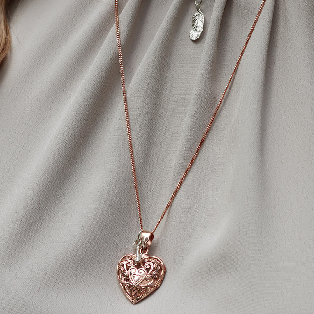 model wearing rose gold curb chain with rose gold filigree heart locket