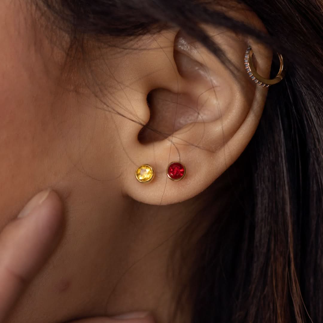 Close up of model wearing garnet mini stud earrings in silver