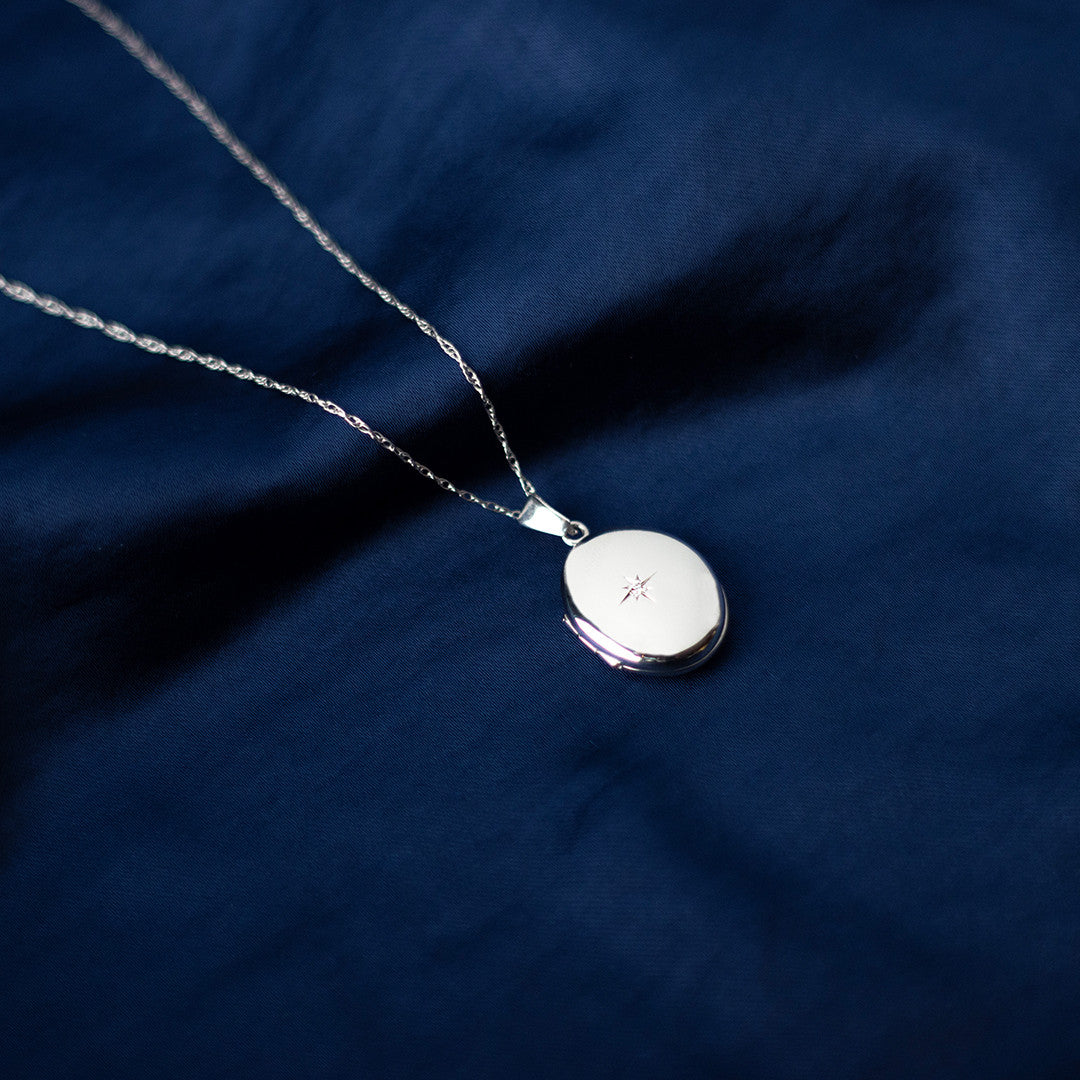 diamond oval locket in white gold on a blue piece of fabric