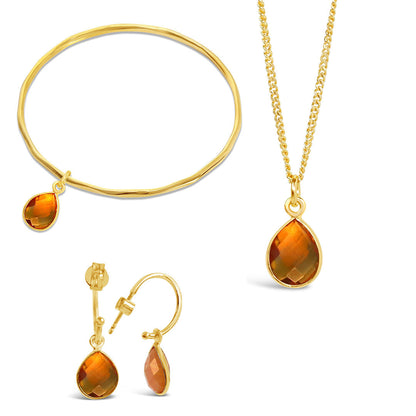 gold citrine charm bangle, necklace and drop hoop earrings on a white background
