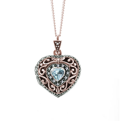 Heart shaped rose gold locket with blue topaz gemstone in centre