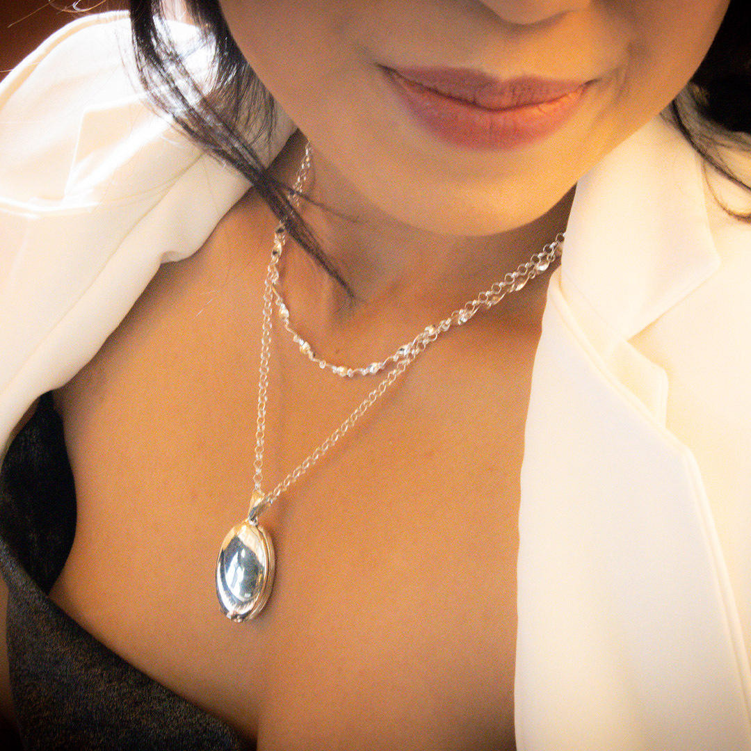 close up of model wearing four picture oval locket in white gold