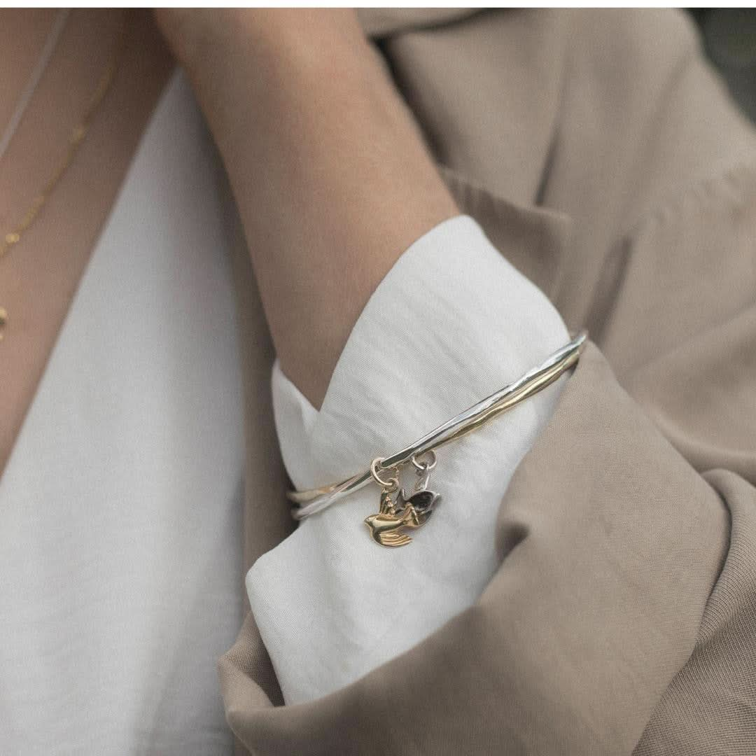 close up of model wearing two bird bangles