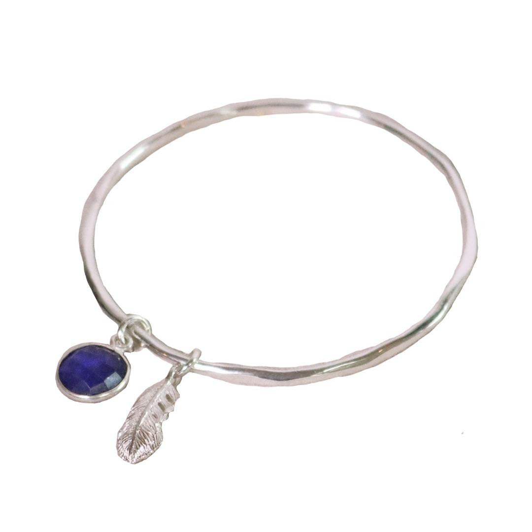silver charm bangle with sapphire birthstone and feather attached