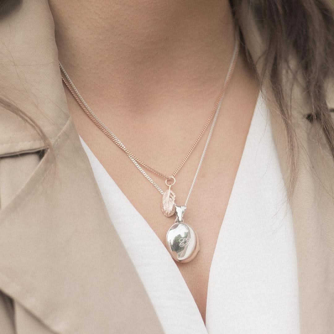 model wearing white gold feather locket with rose gold feather charm attached