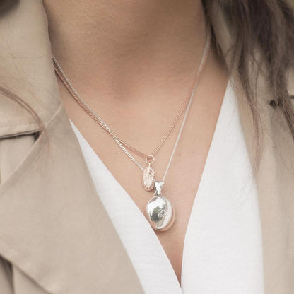 model wearing white gold feather locket with rose gold feather charm attached