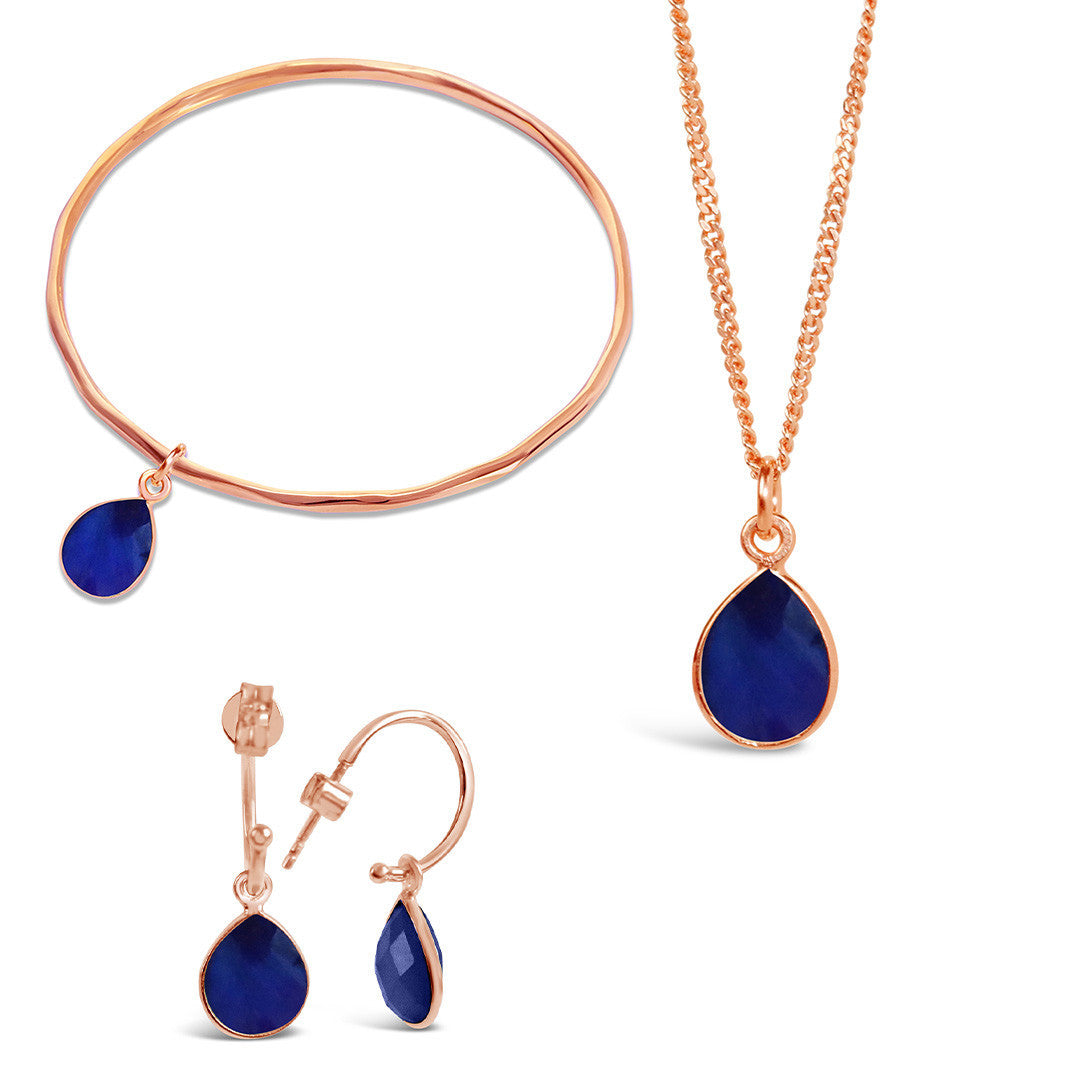rose gold sapphire charm bangle, necklace and drop hoop earrings on a white background