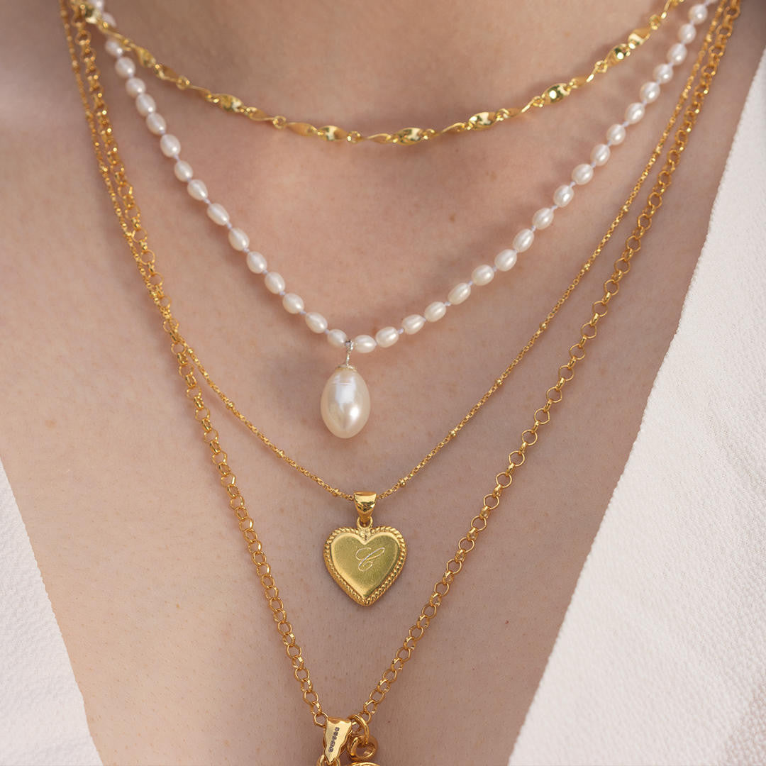 close up of model wearing engravable heart necklace in gold 