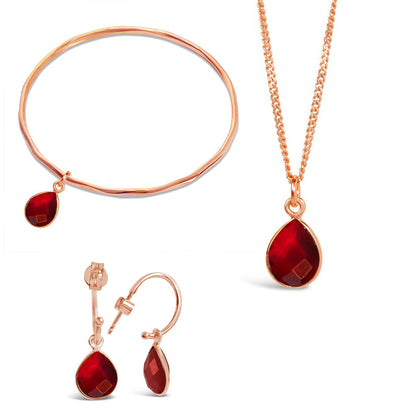 rose gold garnet charm bangle, necklace and drop hoop earrings on a white background