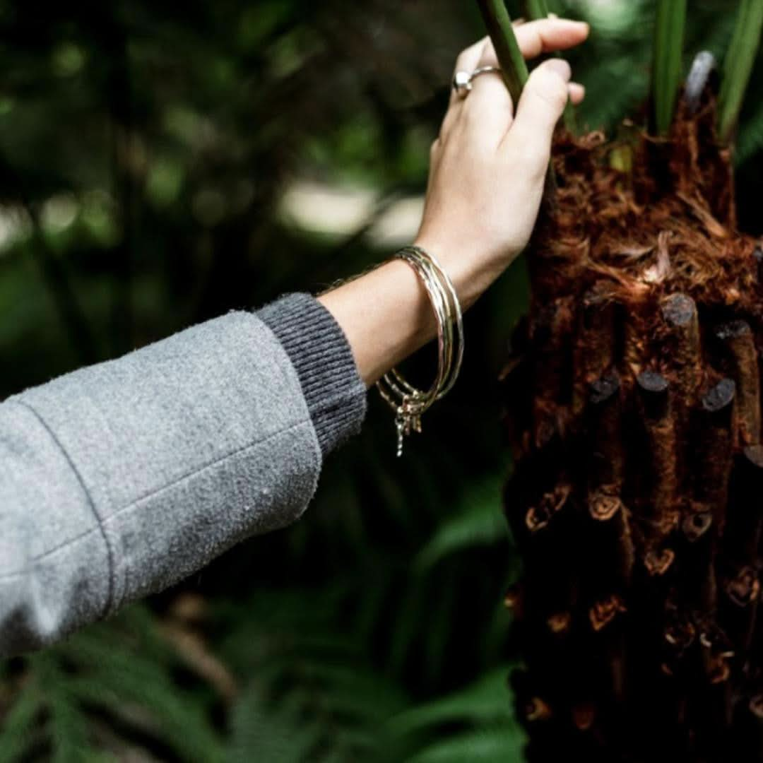 close up of model wearing multiple key bangles in silver