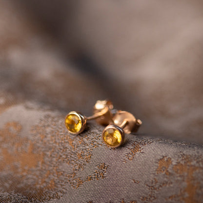 citrine mini stud earrings in rose gold on a piece of fabric