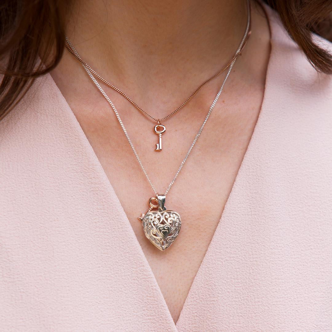 model wearing heart locket in white gold with rose gold key charm on the chain