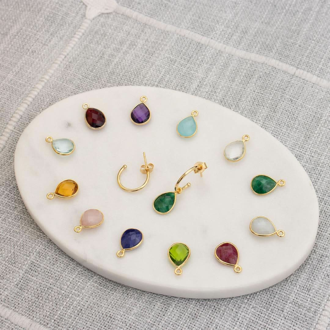 birthstones and drop hoop earrings on a platter