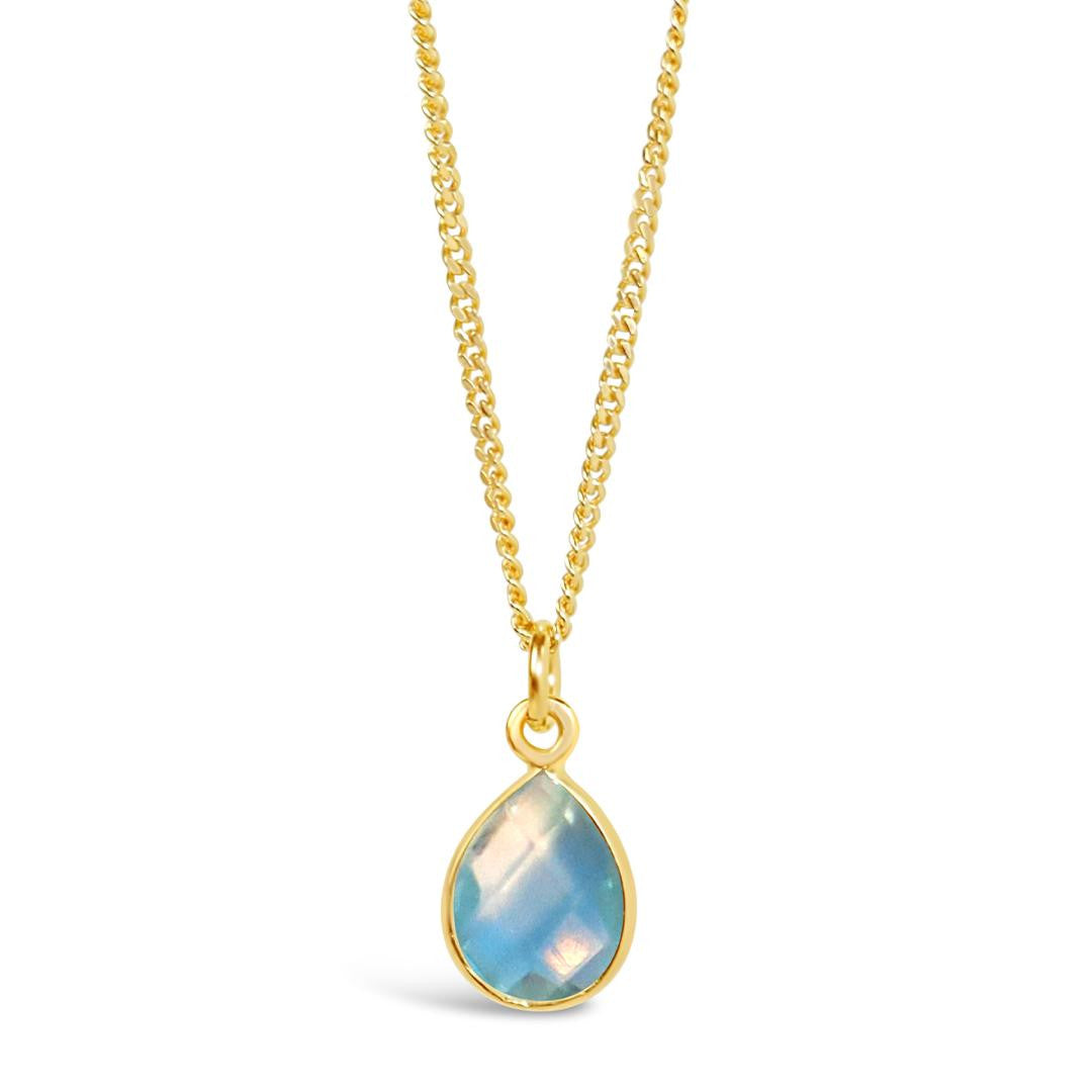blue topaz charm necklace in gold on a white background