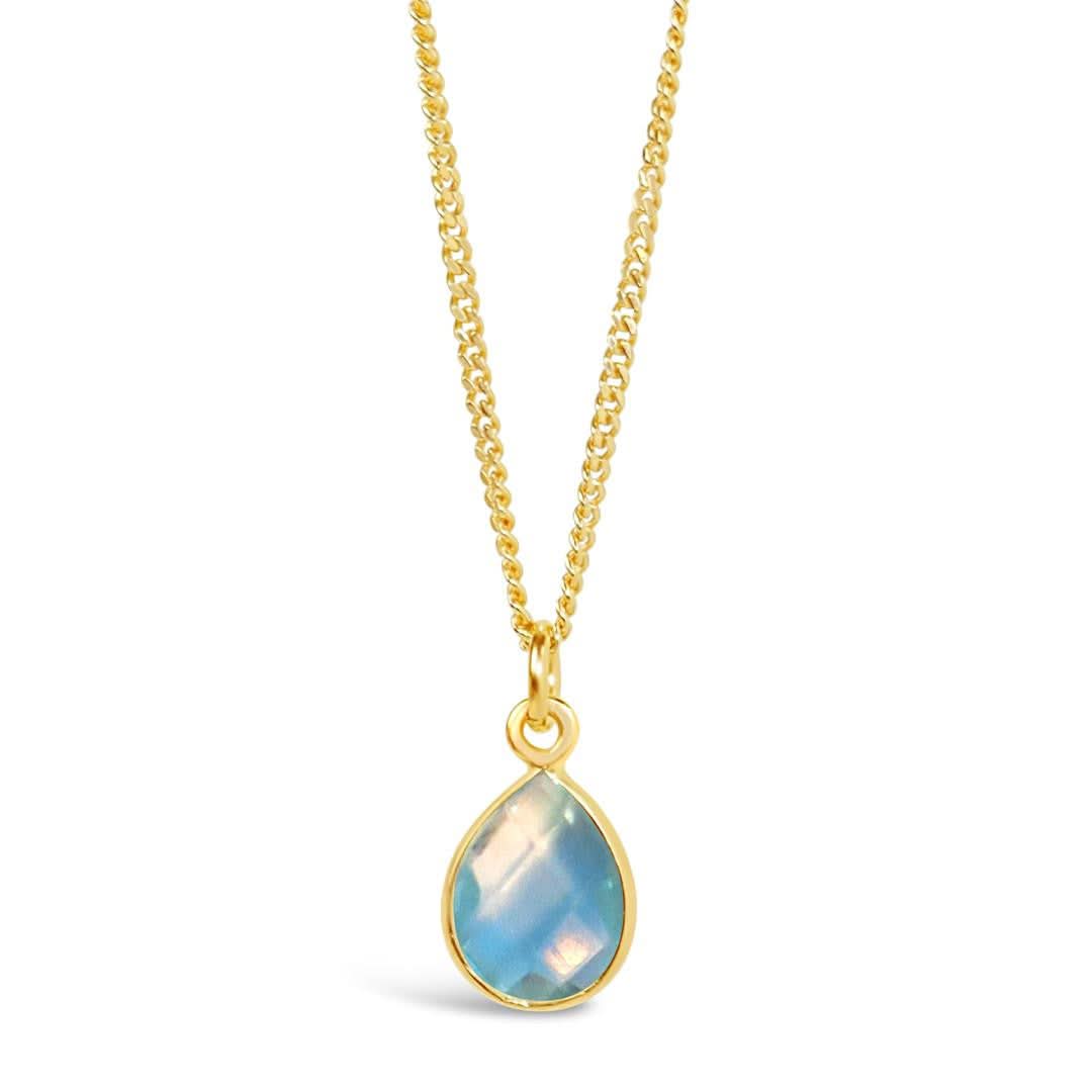 blue topaz charm necklace in gold on a white background