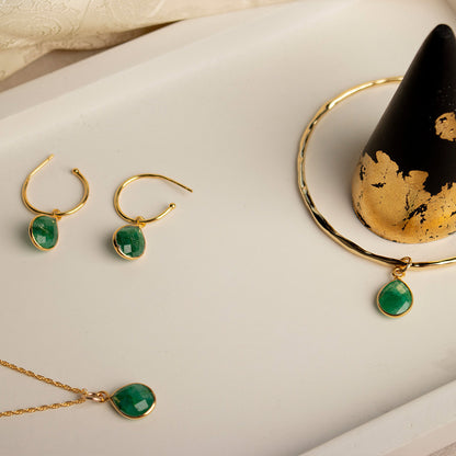 Emerald hoop earrings, necklace and bangle in a marble tray with black ring cone