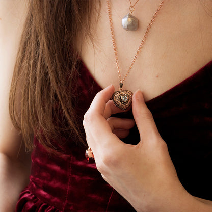 Model holding rose gold heart shaped locket with blue topaz gemstone in centre