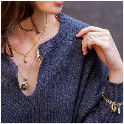 model wearing gold bangle with feather charms attached 