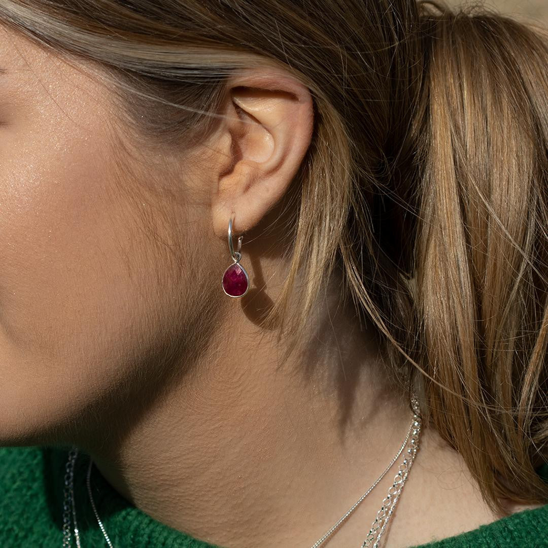 close up of model wearing ruby drop hoop earrings