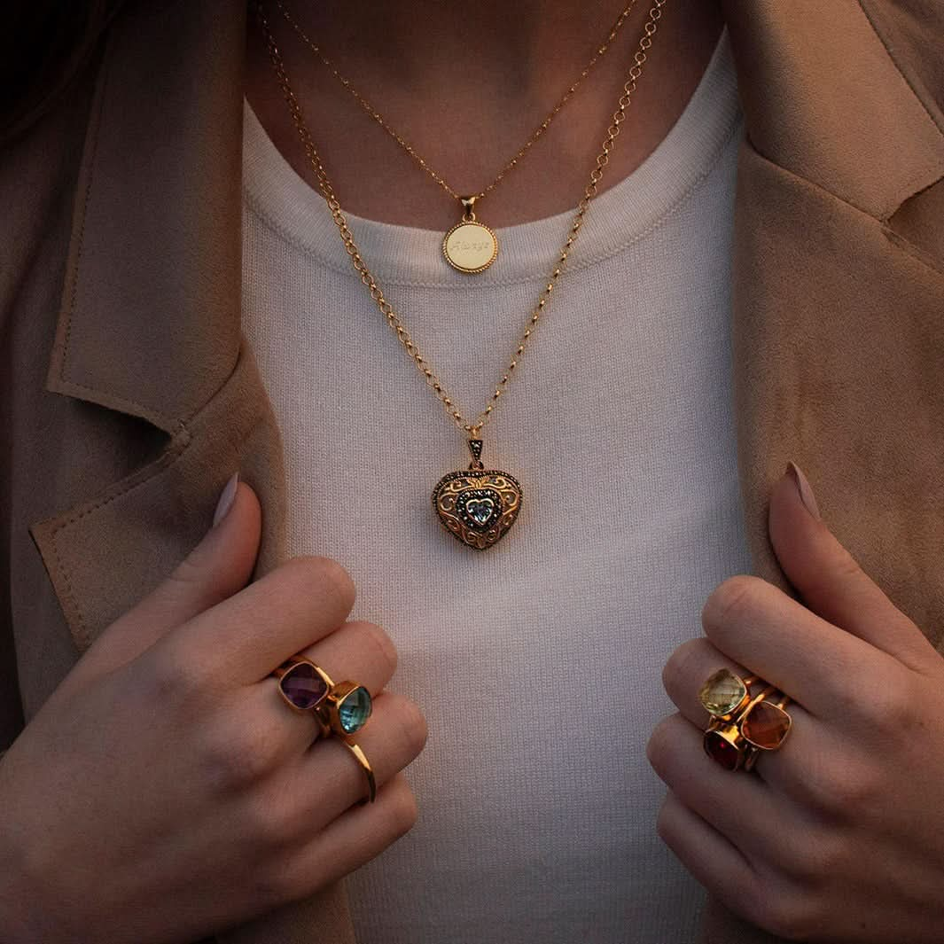 model in white top wearing gold vintage heart locket with topaz gemstone