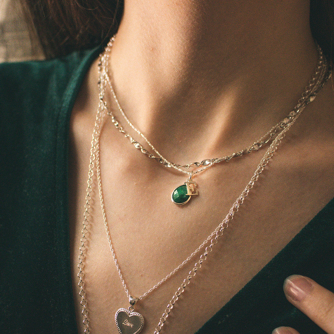 closeup of model wearing emerald charm necklace in silver with initial charm
