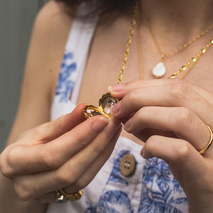 model wearing opened seahorse locket in gold with photos inside