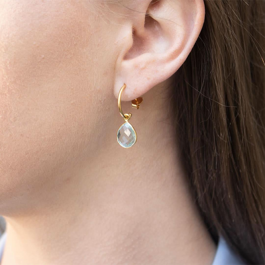 closeup of model wearing blue topaz earrings in silver