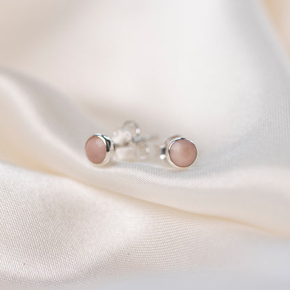 pink opal mini stud earrings in silver on a piece of cream fabric