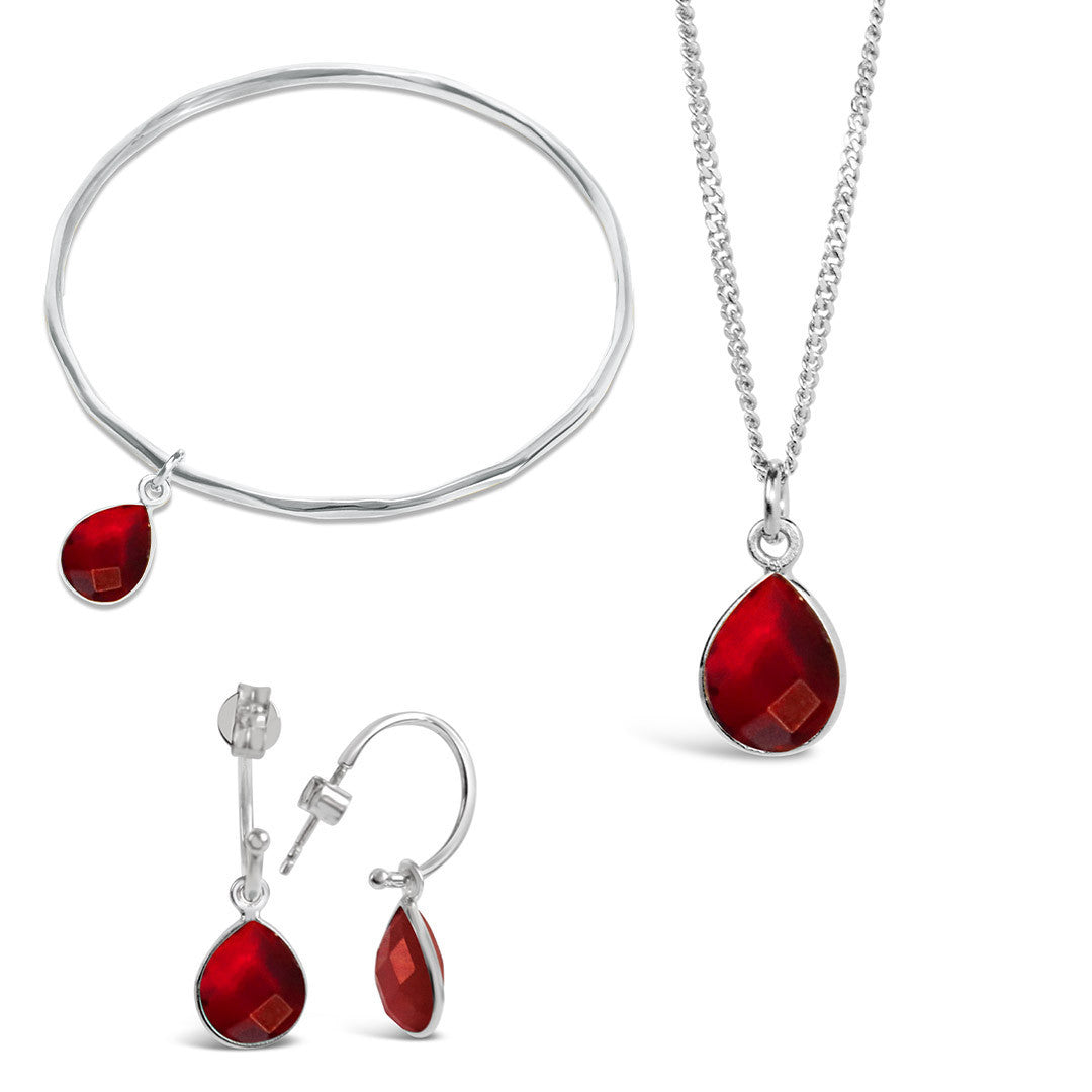 silver garnet charm bangle, necklace and drop hoop earrings on a white background