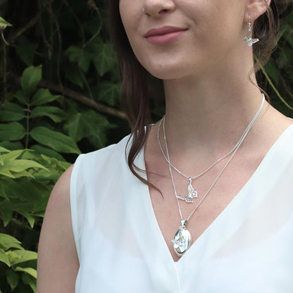 model in white top wearing white gold oval shaped locket with butterfly charm