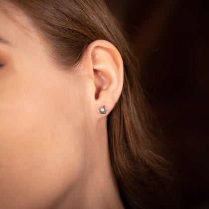 female model wearing heart shaped stud style earrings in silver with a diamond decoration