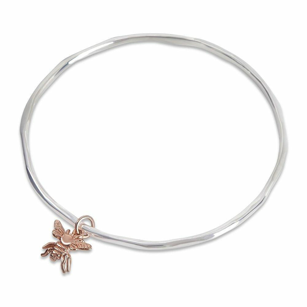 silver bangle with rose gold bee charm on a white background