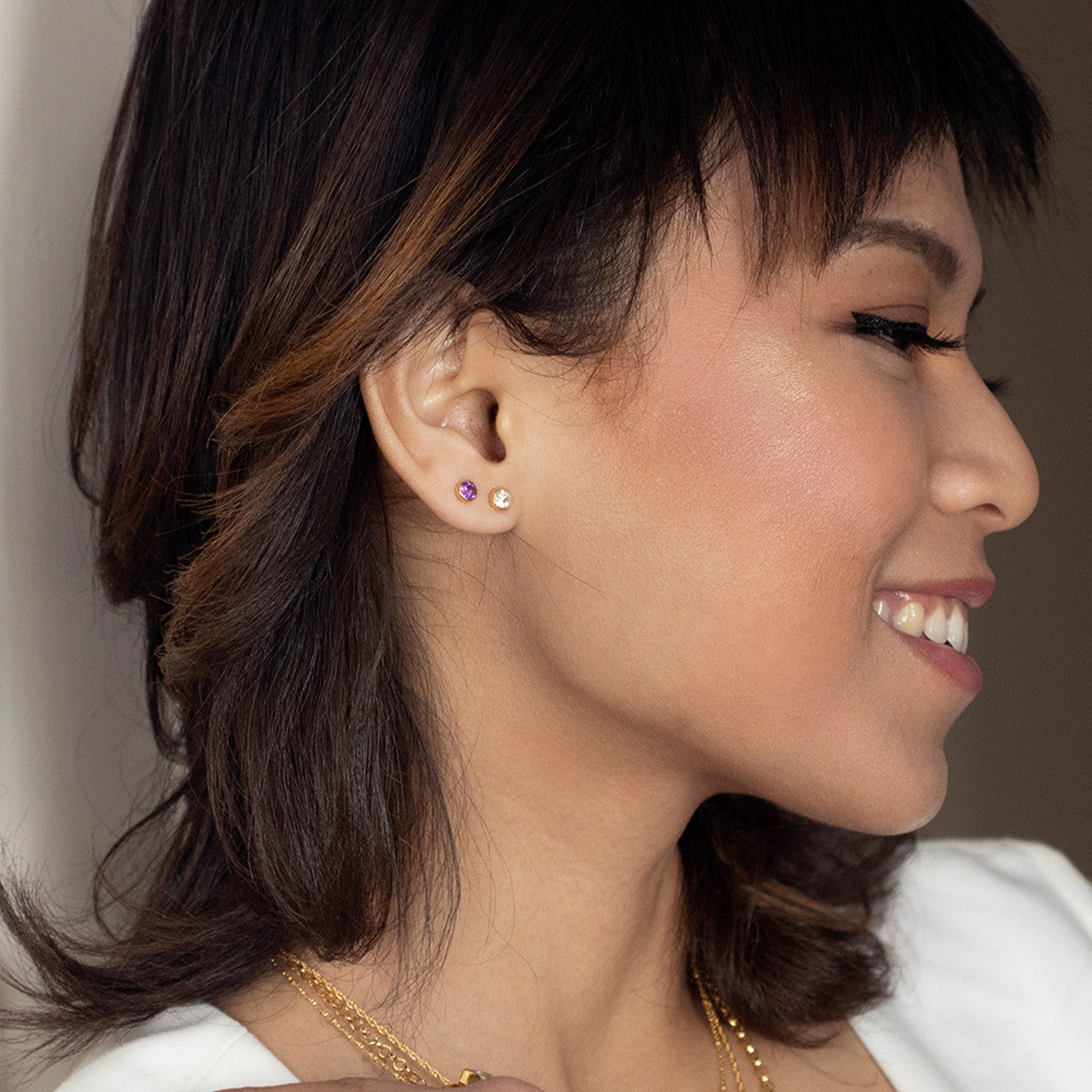 Close up model image wearing white quartz mini stud earrings in gold