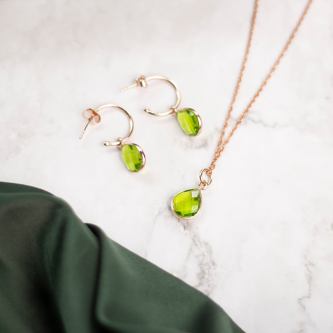 peridot drop hoop earrings and necklace in rose gold on a white background