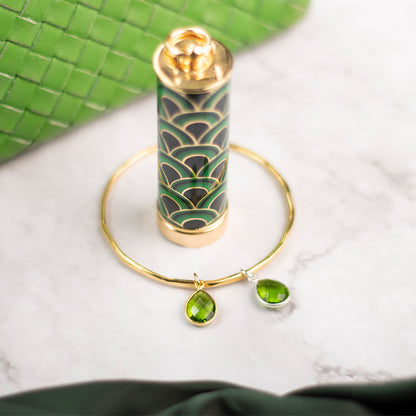 real green peridot teardrop gemstone on a gold thin bangle on a marble tile
