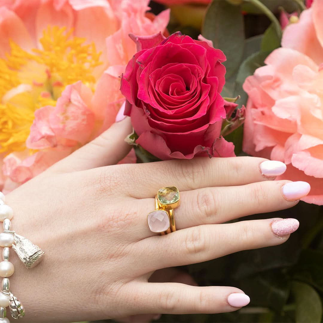 close up of model wearing green amethyst cocktail ring with flowers in the background