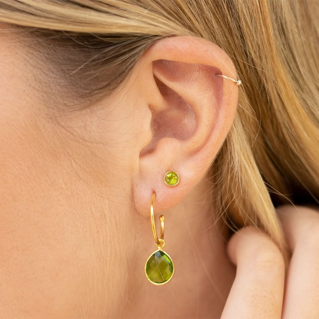 close up of model wearing peridot hoop earrings and stud earrings in gold 