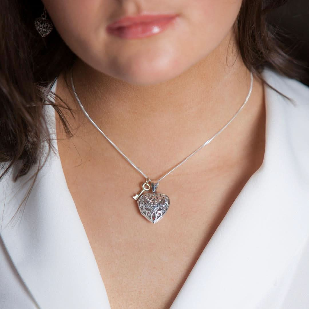 closeup of model wearing key locket in silver with silver key charm on chain