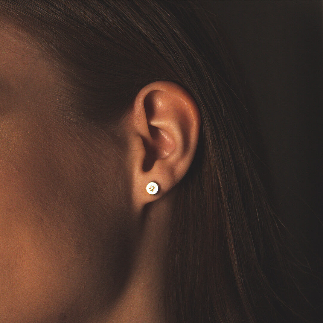 female model wearing a circular shaped stud style earring with a diamond decoration 