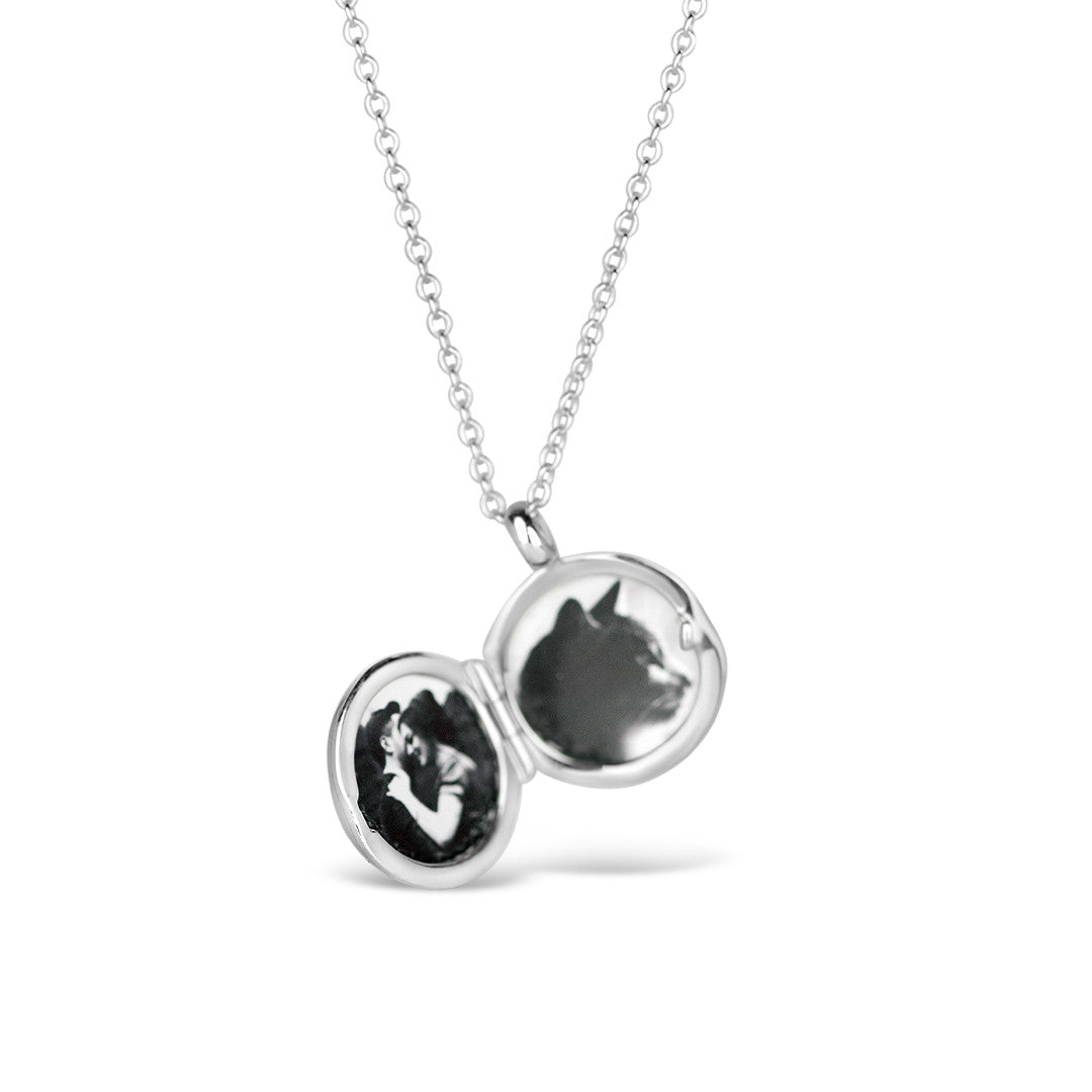 opened small round diamond locket in silver on a white  background