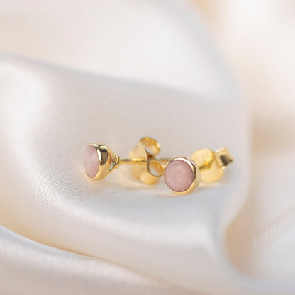 pink opal mini stud earrings in gold on a piece of fabric