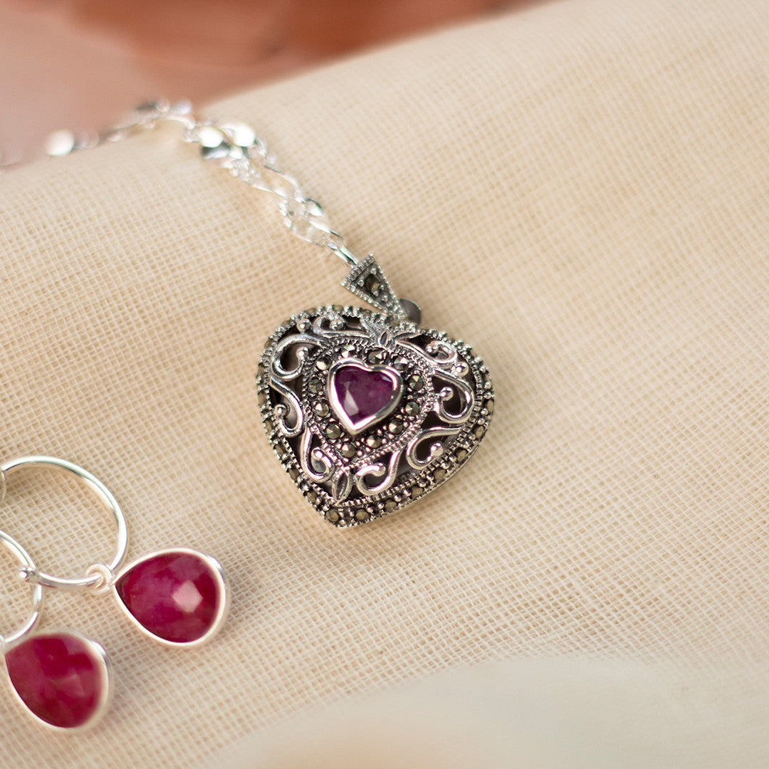 ruby vintage heart locket in silver with ruby droop hoop earrings on a piece of fabric