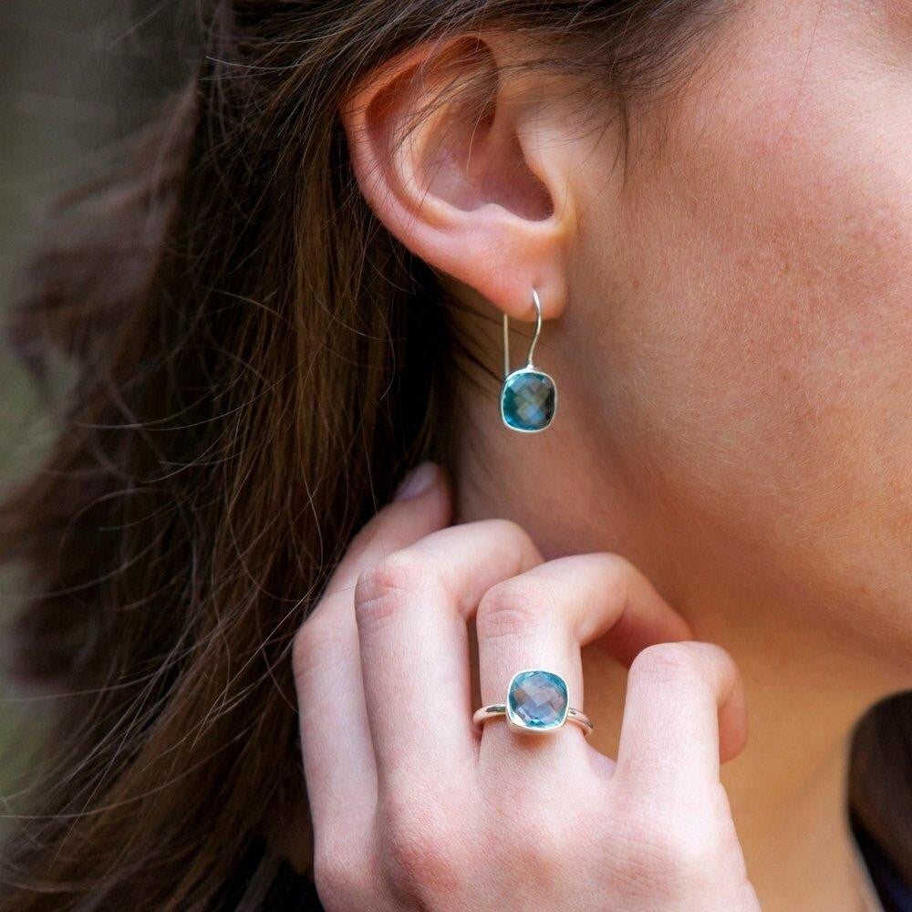 closeup of model wearing blue topaz earrings in silver