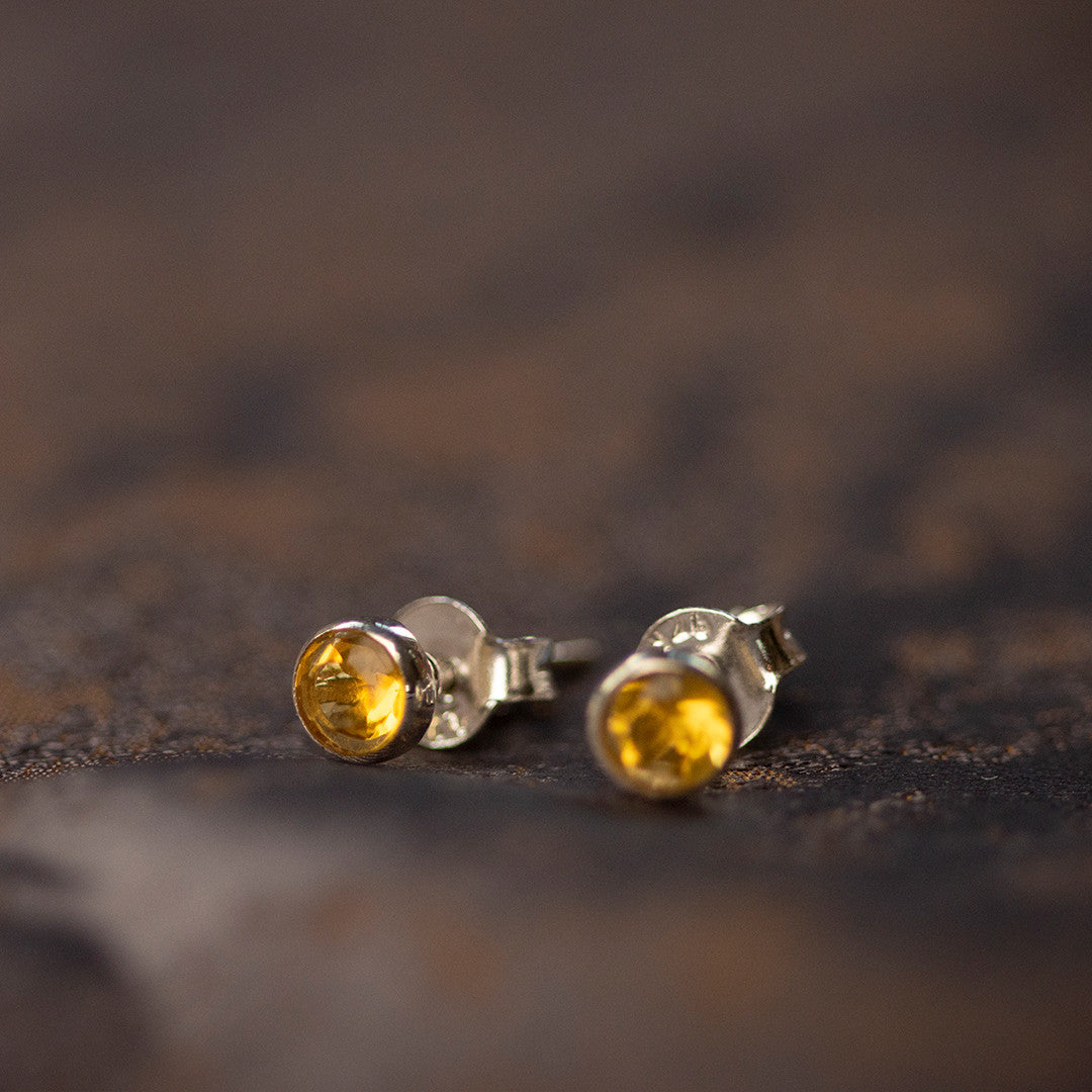 citrine mini stud earrings facing front on piece of fabric
